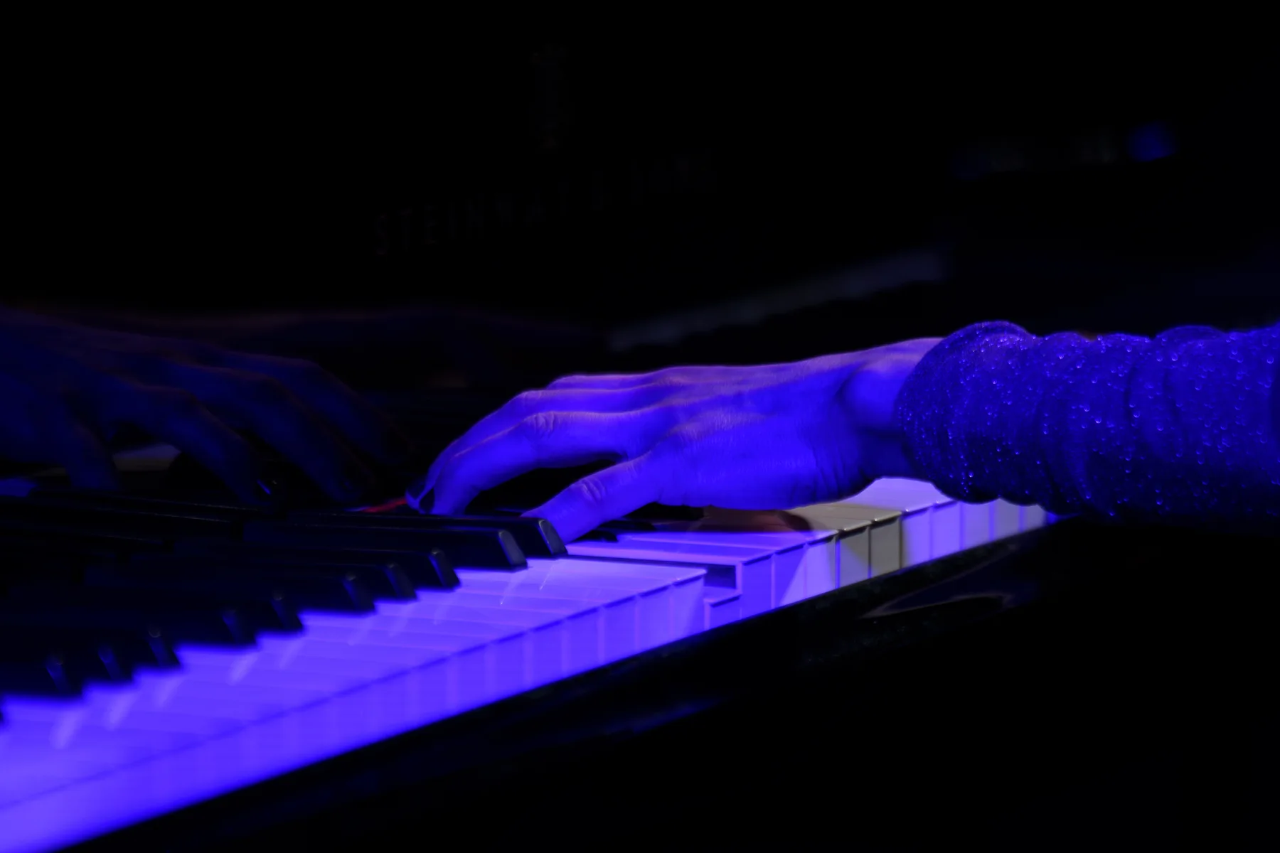 Dłonie pianistki na klawiaturze fortepianu w niebieskim świetle podczas Piano Day 2026